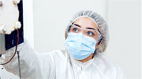Woman in PPE working with reagent manufacturing equipment