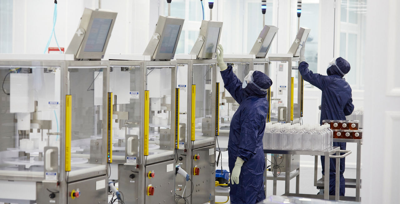 Technicians in PPE operating dispensing machinery in ISO certified cleanroom